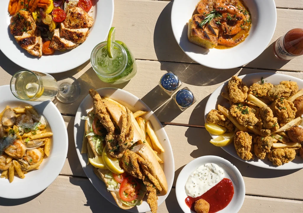 Bright overhead view of diverse dishes and beverages on a wooden table.