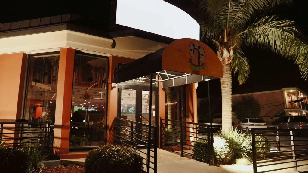 Orange restaurant exterior at night with a tall palm tree.