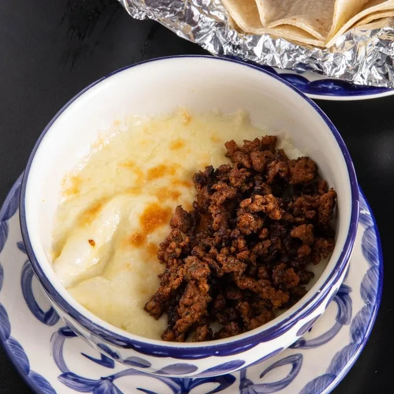 Close-up of melted queso fundido with chorizo and tortillas.