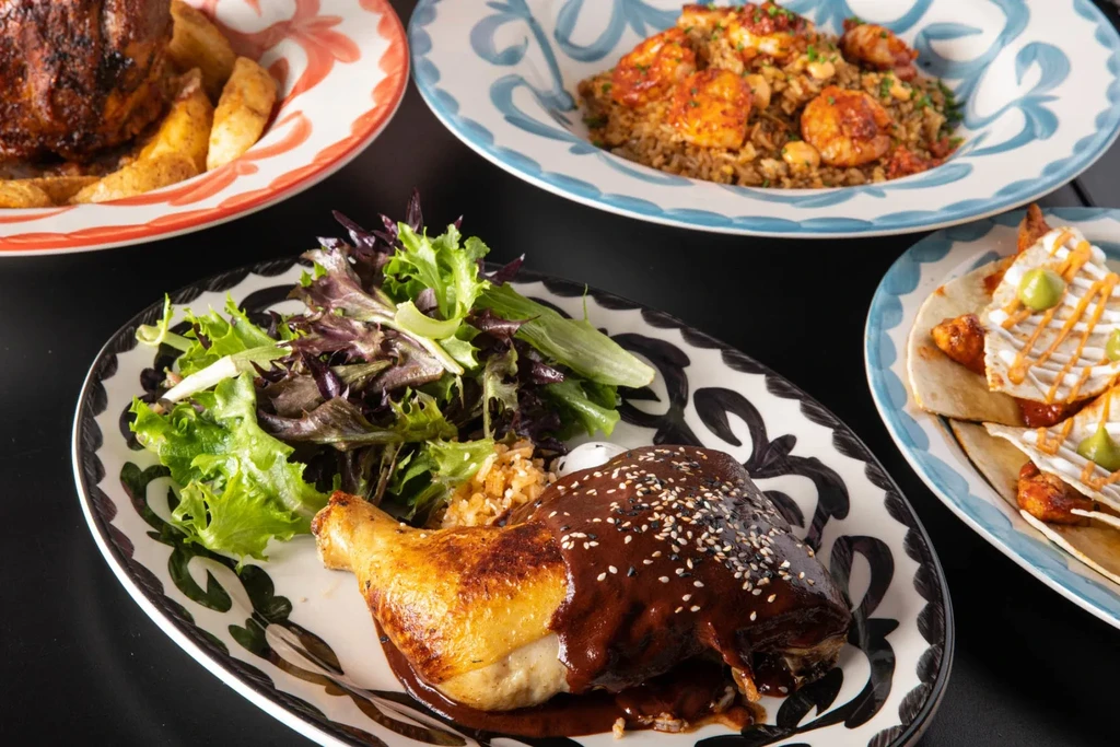 Vibrant spread of roasted chicken with mole and other dishes.