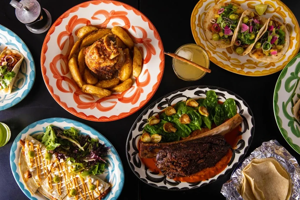 Flat lay of diverse Mexican cuisine and drinks on ornate plates.