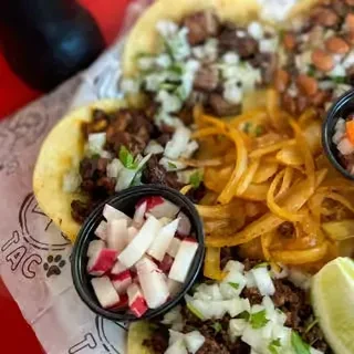 Overhead: street tacos with meat, onions, cilantro, radishes, salsa, lime.