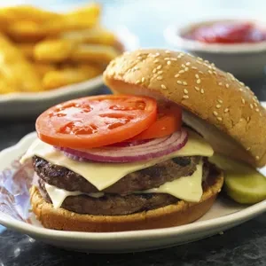 Double cheeseburger with tomato, onion, pickle, fries, and ketchup.