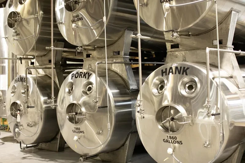 Stainless steel industrial tanks named HAMM, PORKY, HANK, 1860 gallons.