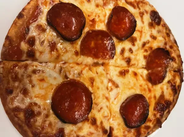 Sliced pepperoni pizza with bubbly cheese and curled pepperoni.