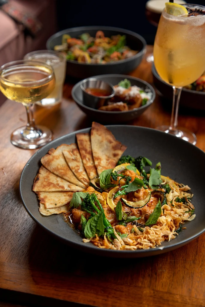 Vibrant restaurant table with a plated dish, flatbread, drinks, and appetizers.