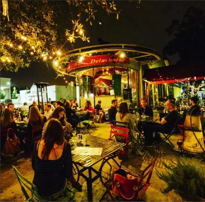 Delachaise Wine Bar's lively patio at night, illuminated by string lights.