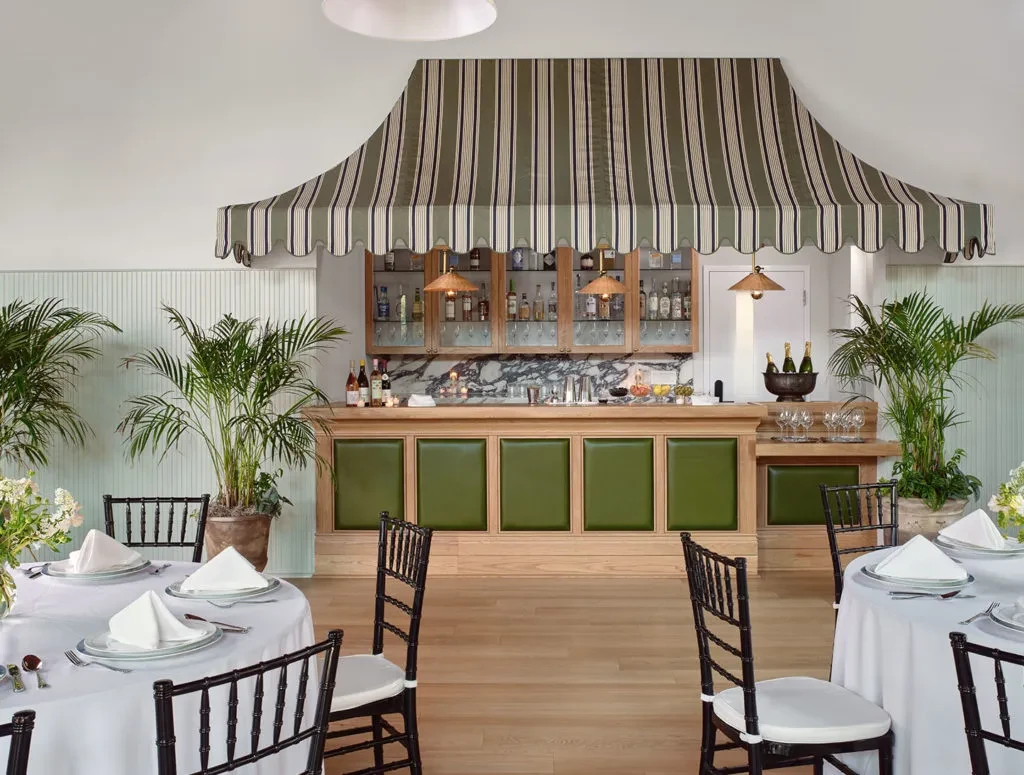 Sophisticated restaurant interior with a prominent striped bar and set tables.