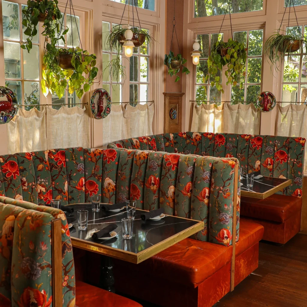 Sunlit restaurant dining room with green floral U-shaped booths.