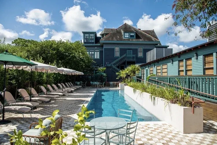 Rectangular pool, lounge chairs, hotel buildings, and sunny blue sky.