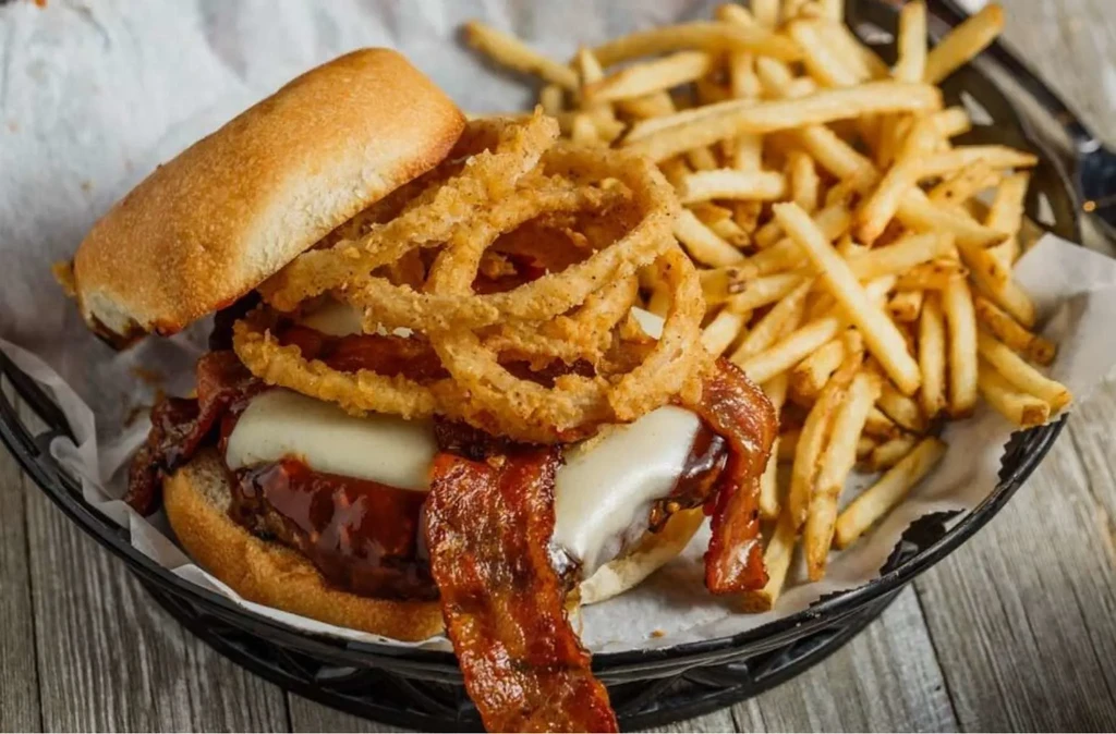 Burger with melted cheese, bacon, onion rings, and crispy fries.