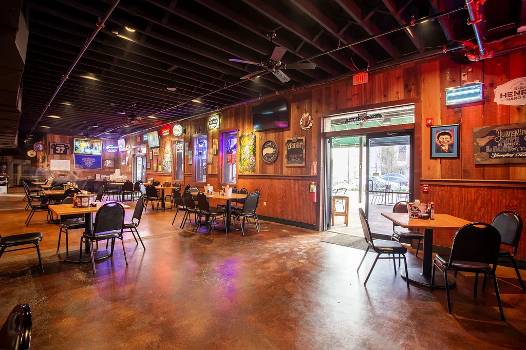 Sports bar interior with wooden paneling, TVs, and sports memorabilia.