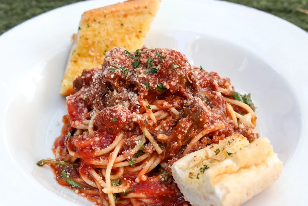 Serving of spaghetti and meatballs with Parmesan, herbs, and garlic bread.