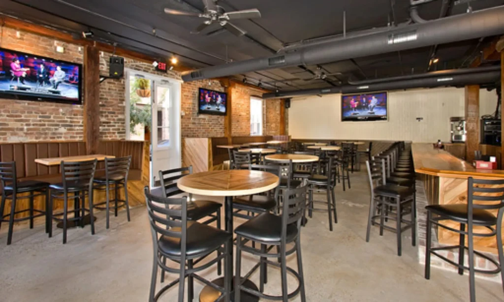 Empty industrial-rustic restaurant interior with brick walls and wooden bar.