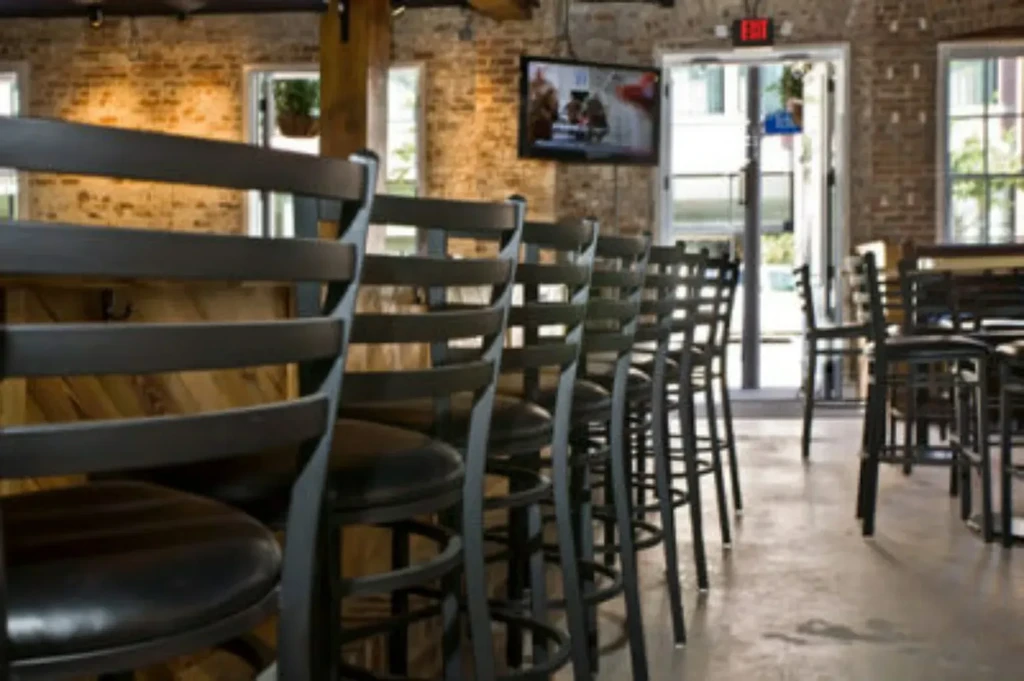 Restaurant interior with a long row of dark bar stools and brick walls.