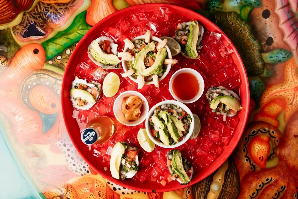 Overhead: Fresh oysters, ceviche, shrimp, and Corona beer on a red ice tray.