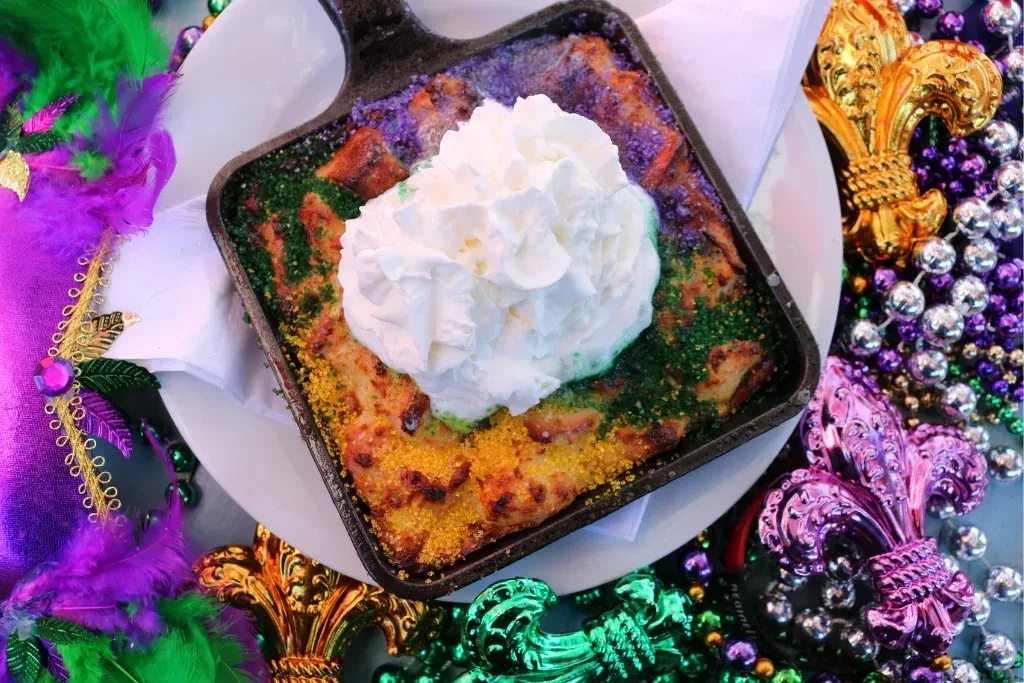 Overhead Mardi Gras dessert with whipped cream, sprinkles, and festive decorations.