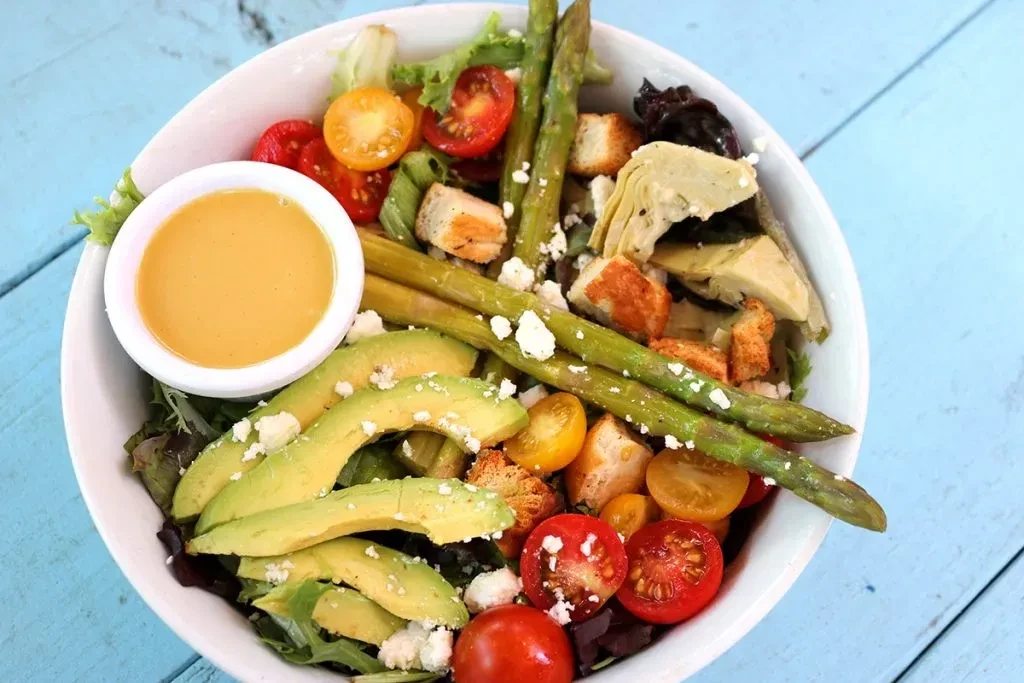 Overhead view of vibrant salad with avocado, tomatoes, and feta.