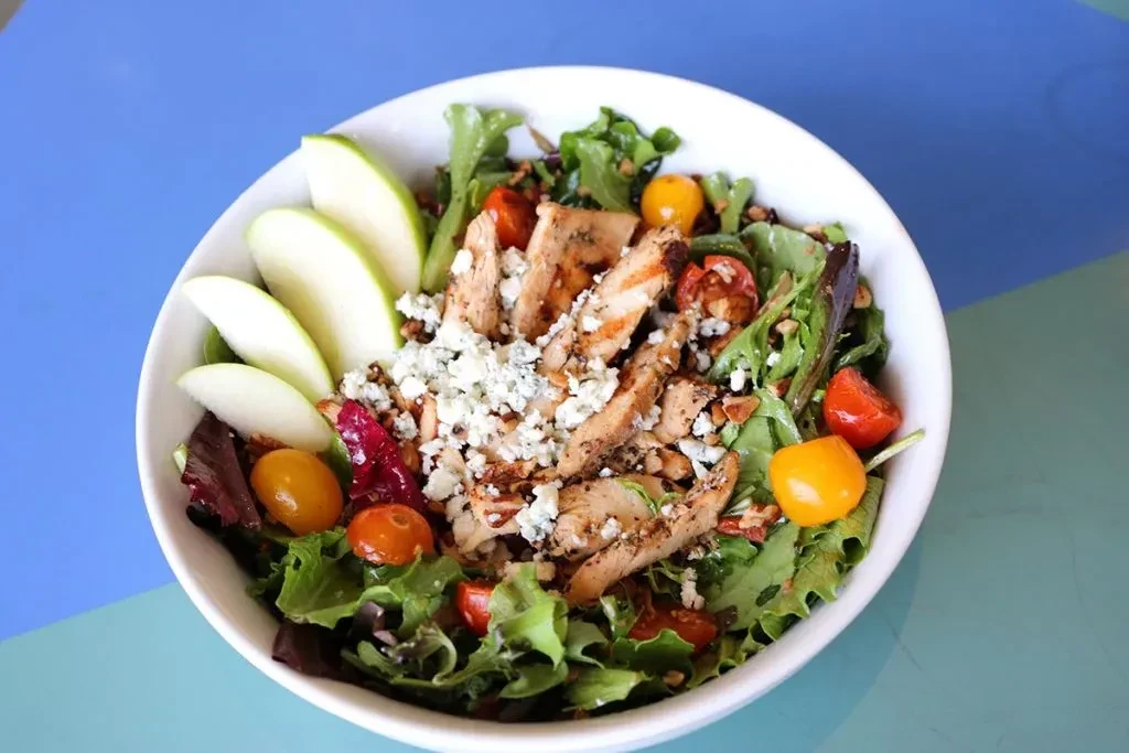 Grilled chicken salad with mixed greens, blue cheese, apples, and tomatoes.