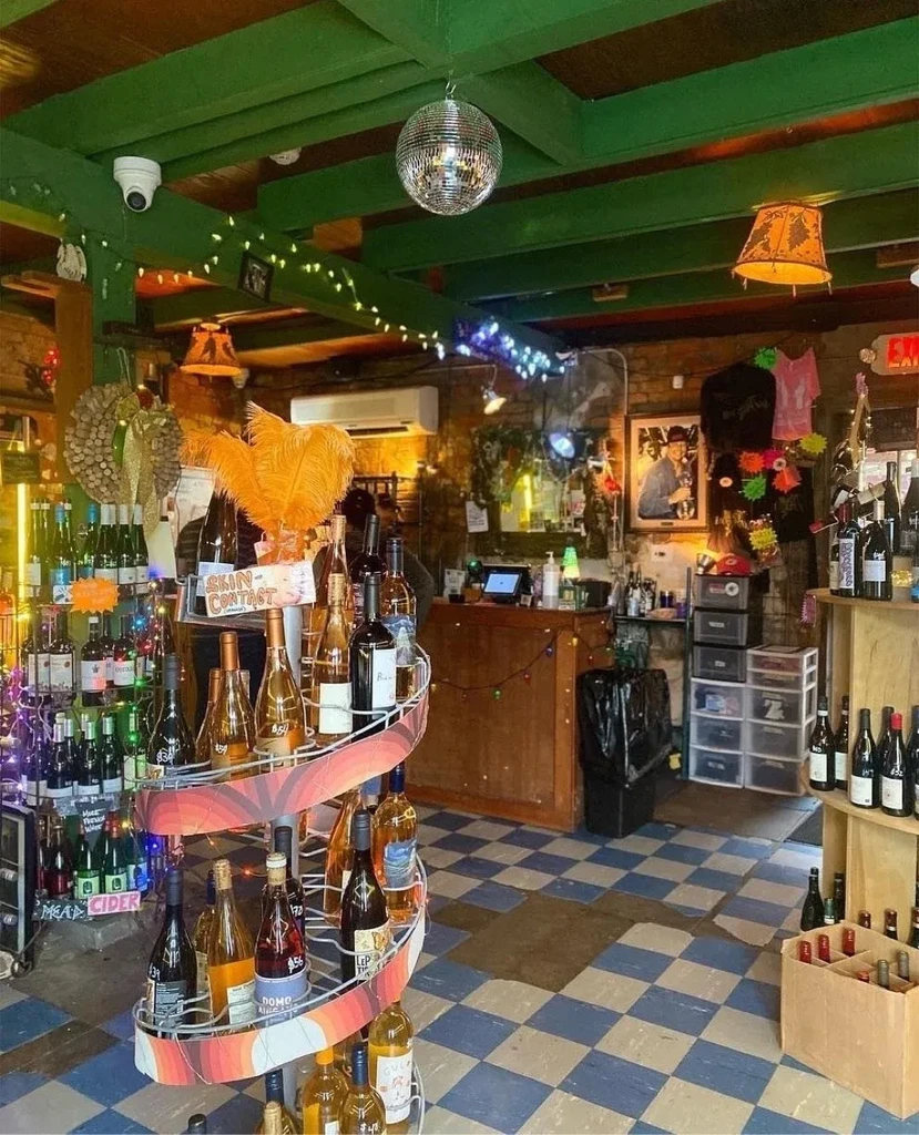 Cozy bar interior with wine displays, a disco ball, and checkerboard floor.