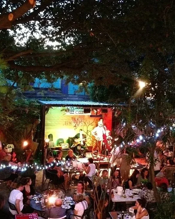 Outdoor restaurant at night with live band and many patrons.