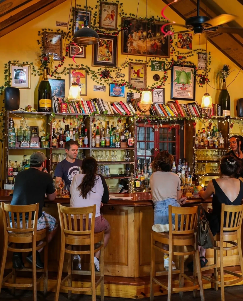Bartender serves four patrons at a colorful, art-filled bar.