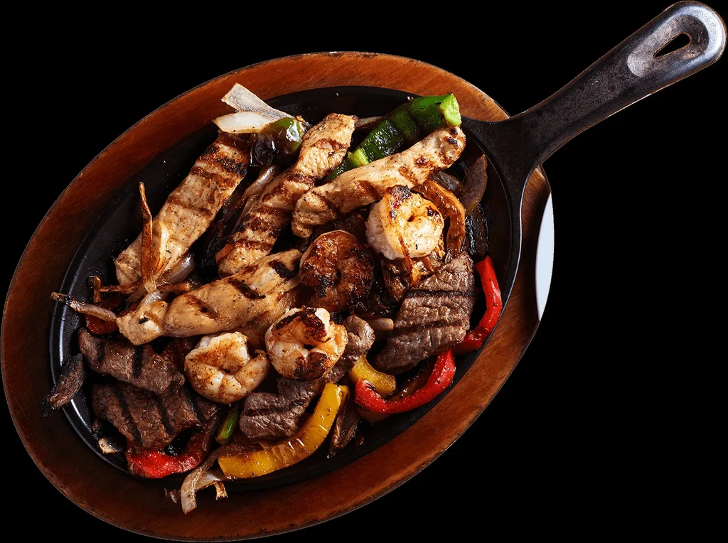 Sizzling chicken, beef, shrimp fajitas with peppers and onions in skillet.