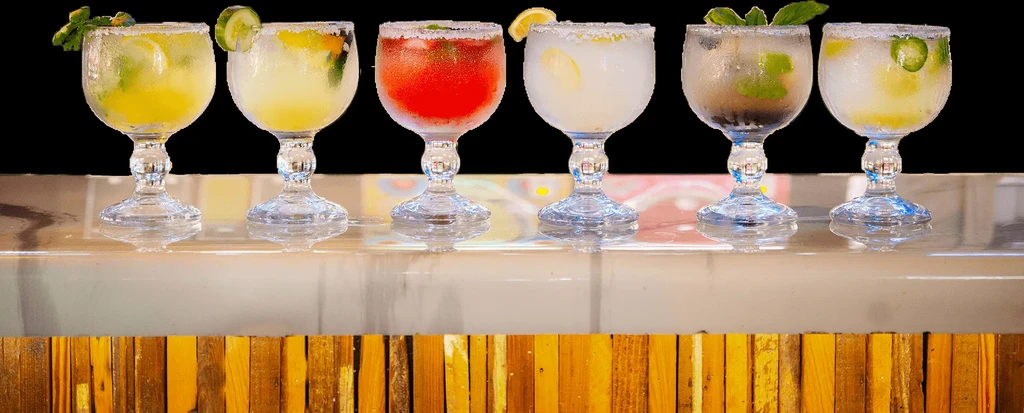 Six diverse, cold cocktails with salted rims and various garnishes.