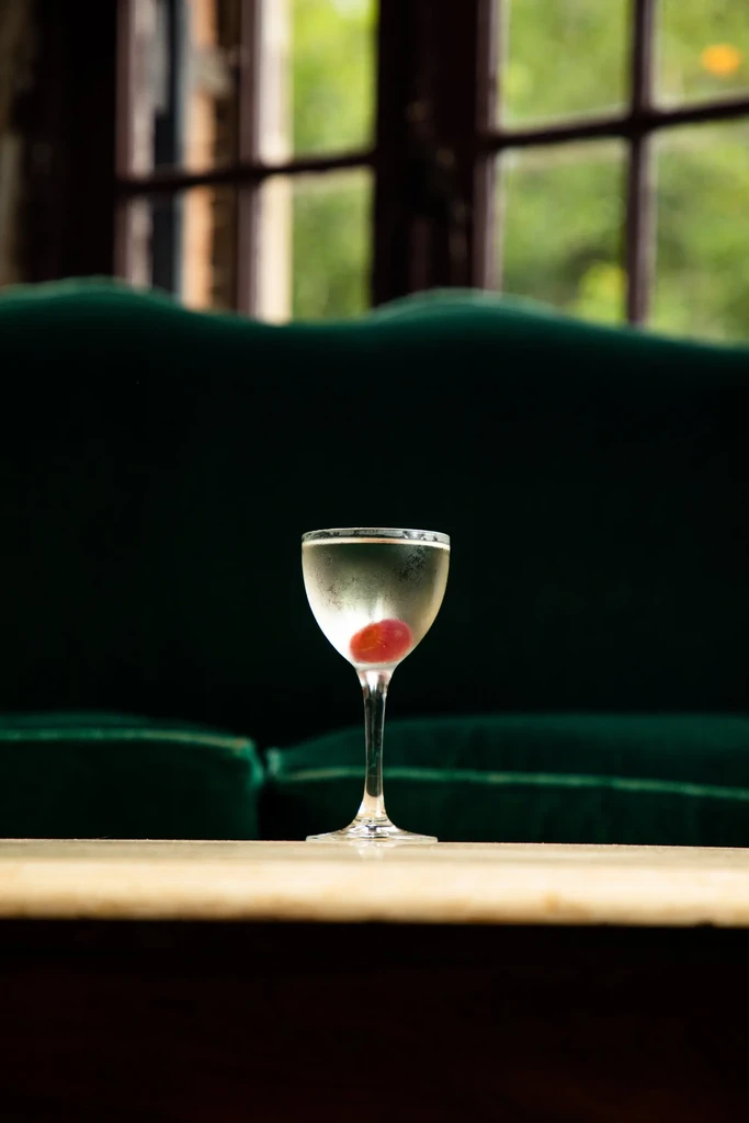 Martini glass with cherry, condensation, and blurred green background.