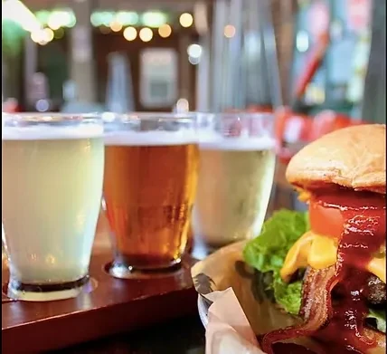 Burger with bacon and cheese alongside a three-glass beer flight.