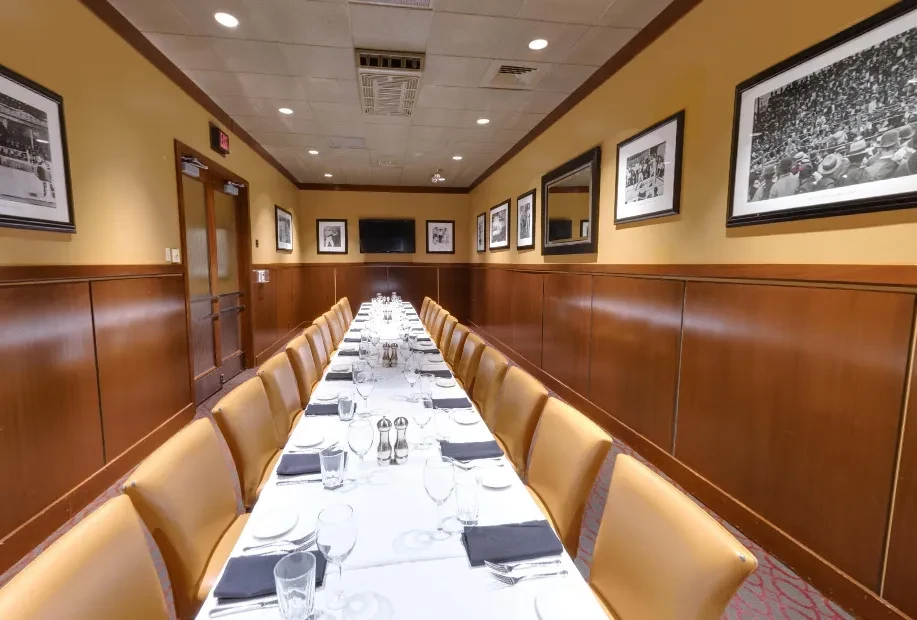 Long, empty private dining room with a set table and mustard walls.