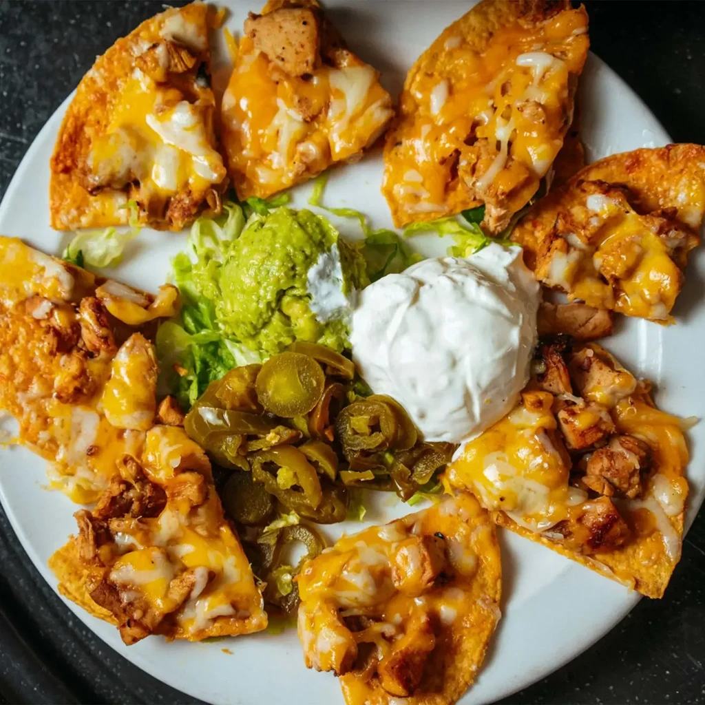 Loaded chicken nachos with melted cheese, guacamole, sour cream, and jalapeños.