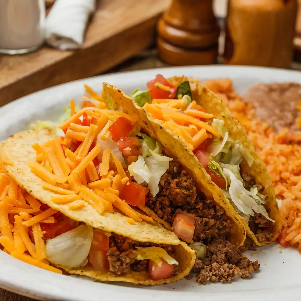 Three crispy hard-shell beef tacos with rice and beans.