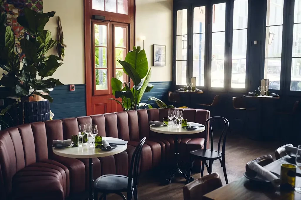 Elegant restaurant interior with curved brown leather booth and set tables.