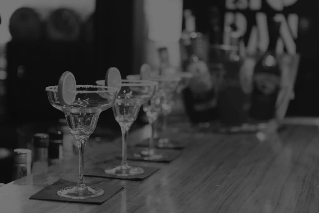 Black and white margarita glasses with lime and salt on a bar.