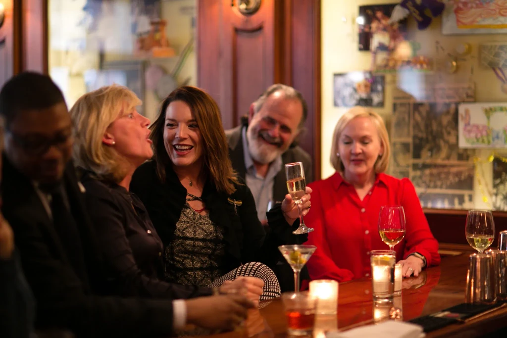 People socialize and enjoy various drinks at a warmly lit bar.