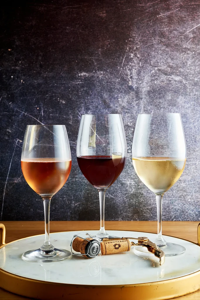 Three chilled wines, corks, and corkscrew on a marble tray.