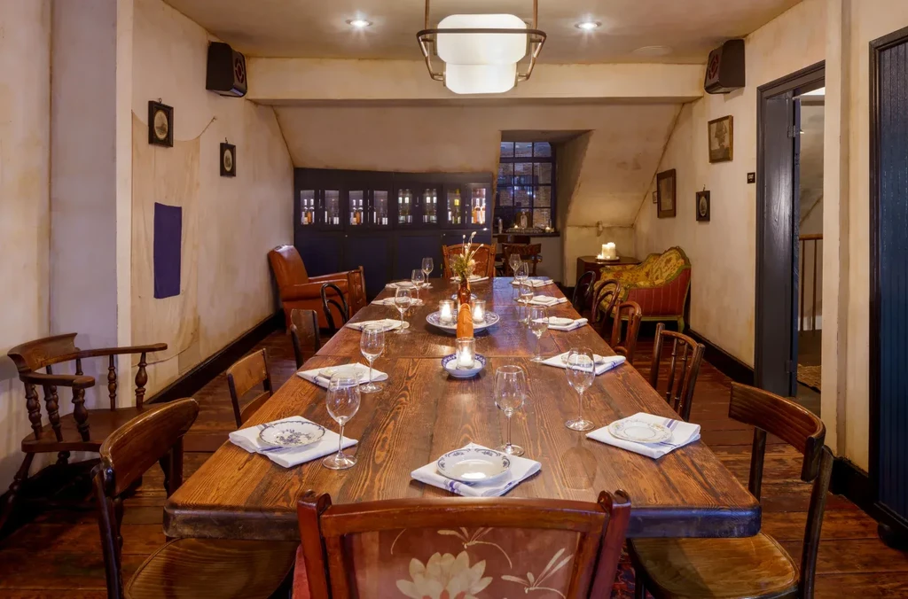 Warmly lit private dining room, long rustic table set for twelve.