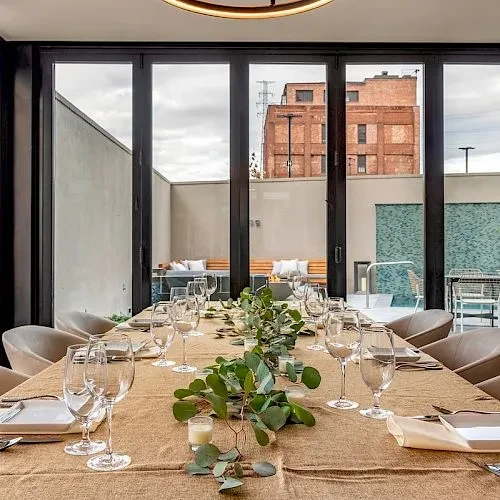 Modern, elegantly set dining table with rustic centerpiece overlooking patio.