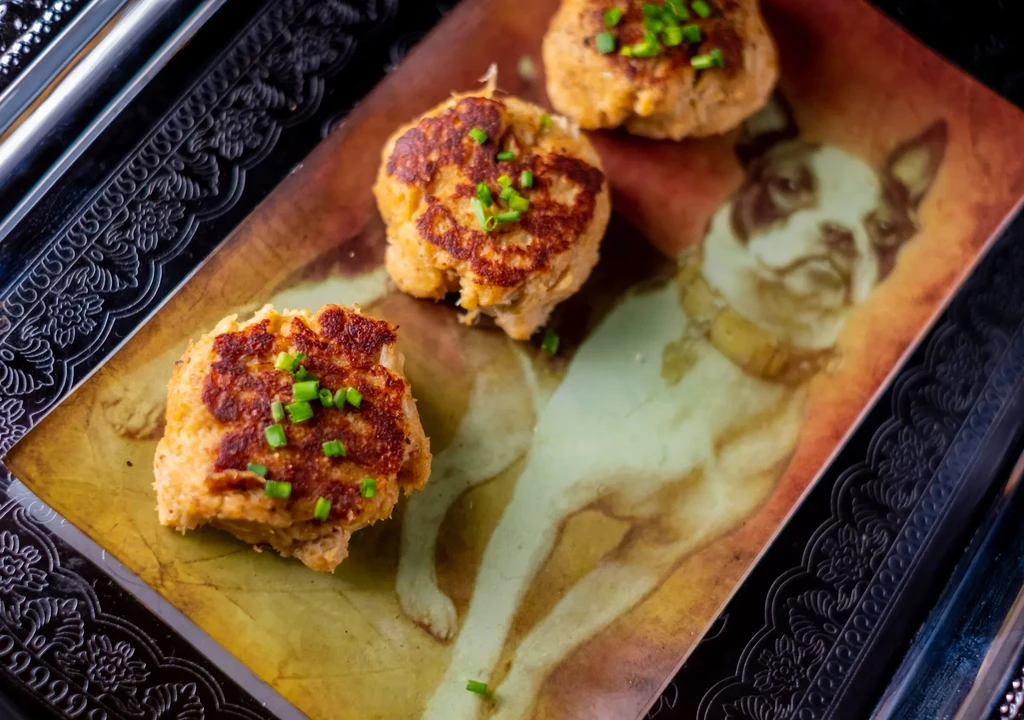 Three golden-brown fritters with chives on a Boston Terrier platter.