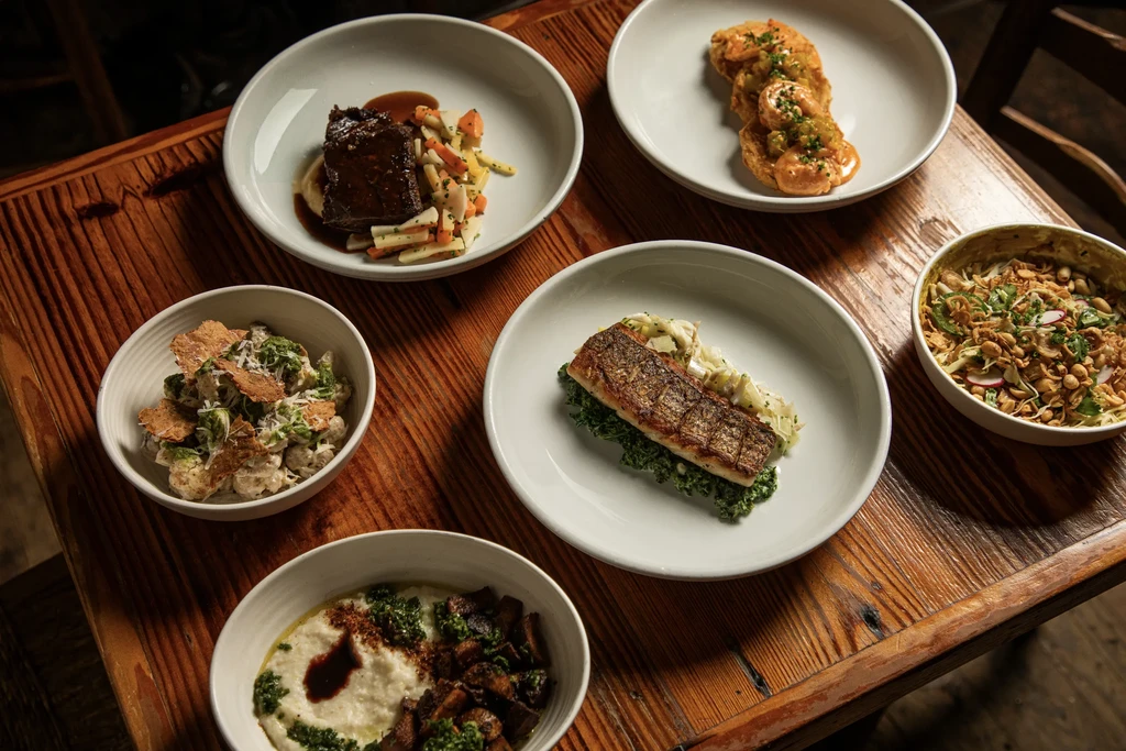 Overhead view of six artfully presented dishes on a rustic table.
