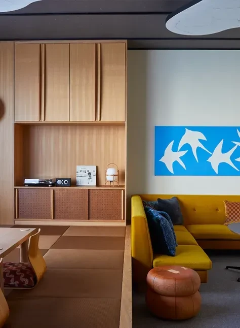 Modern lounge with yellow sofa, record player, and blue bird artwork.