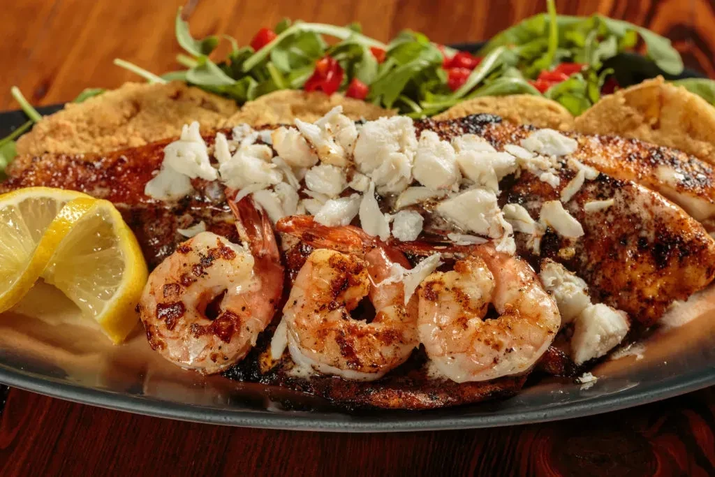 Seafood platter with grilled shrimp, seared fish, crab, and lemon.