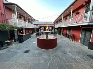 Outdoor courtyard with red buildings, string lights, and a modern bar.