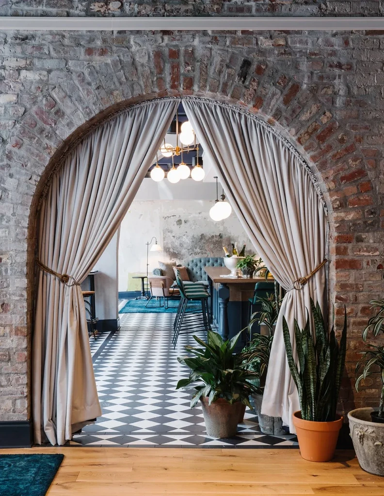 Grand brick archway with drapes frames stylish restaurant interior.