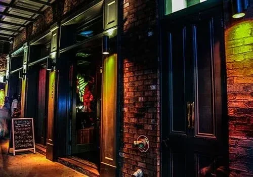 Colorful brick restaurant exterior at night, with a sidewalk chalkboard.