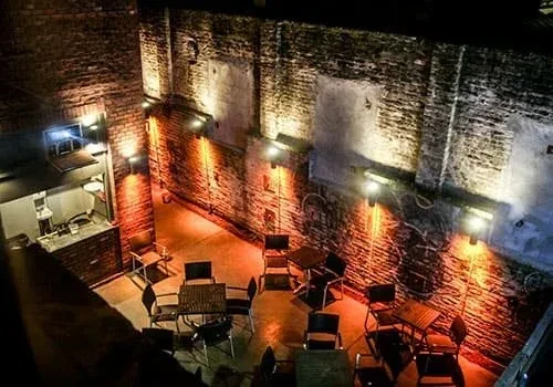 Empty brick patio at night, dramatically lit walls and tables.
