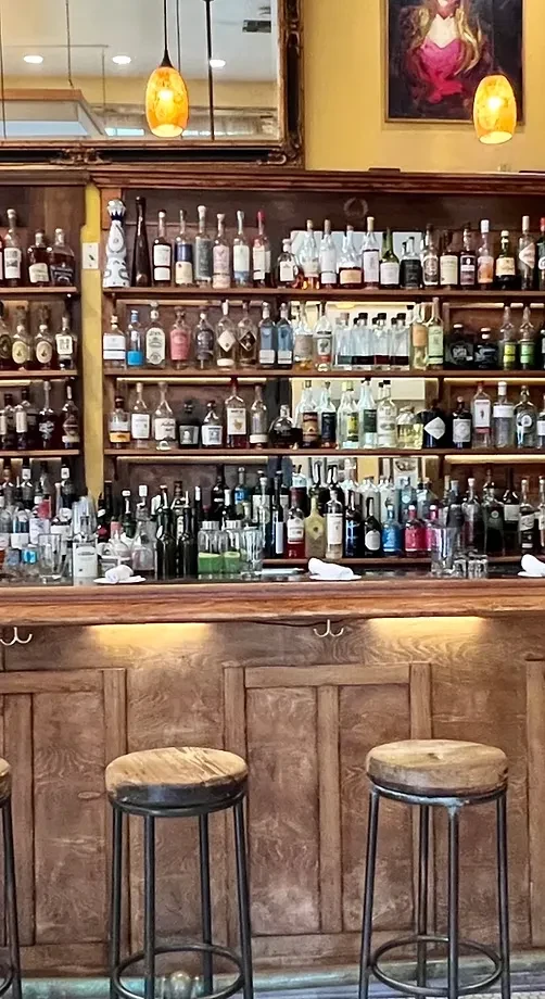 Interior of a well-stocked bar with many liquor bottles and bar stools.