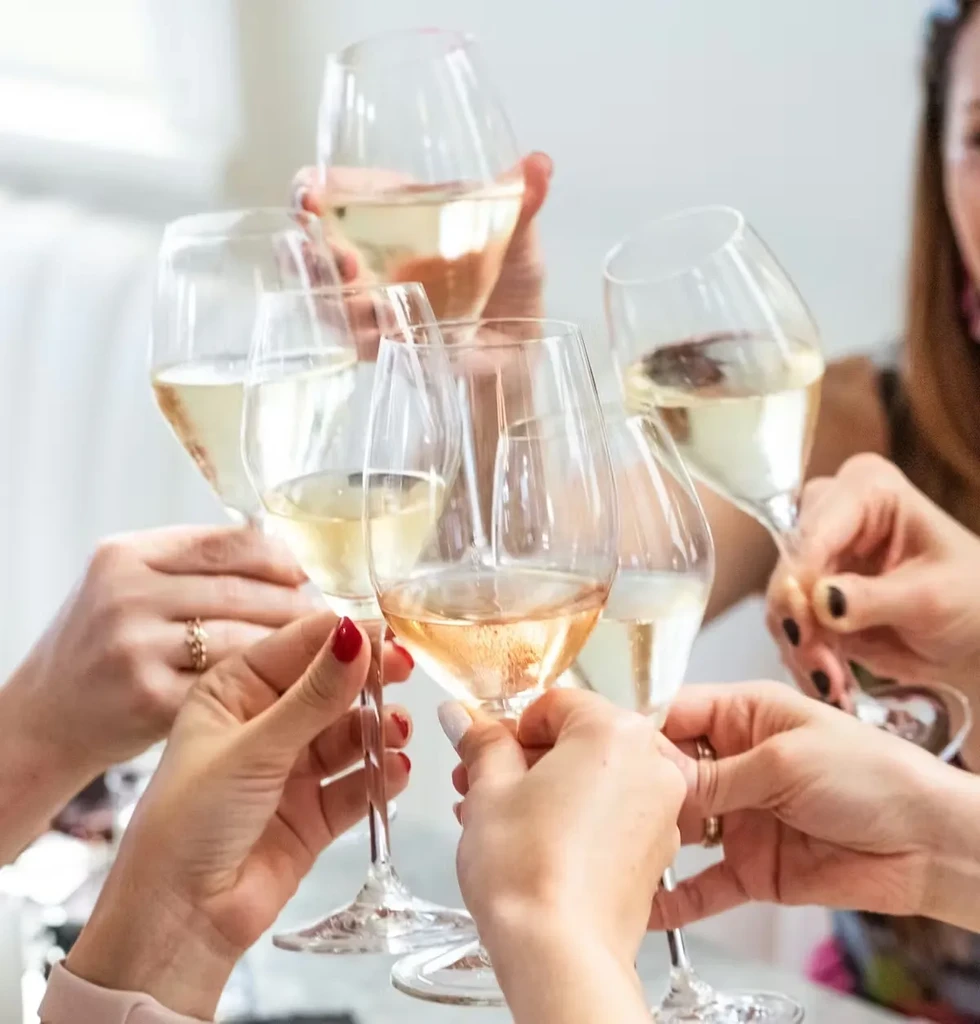 Close-up of diverse hands clinking wine glasses in a toast.