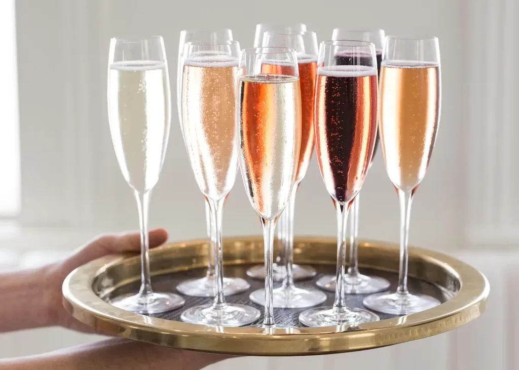 Server holds tray with eight colorful sparkling champagne flutes.